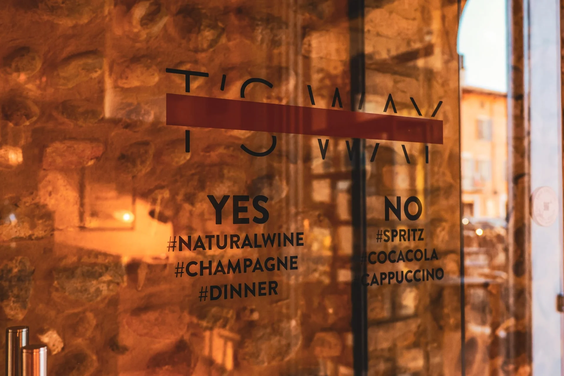 La vetrina di T'S WAY con il logo e le scritte sul vetro, affacciata sulla piazza